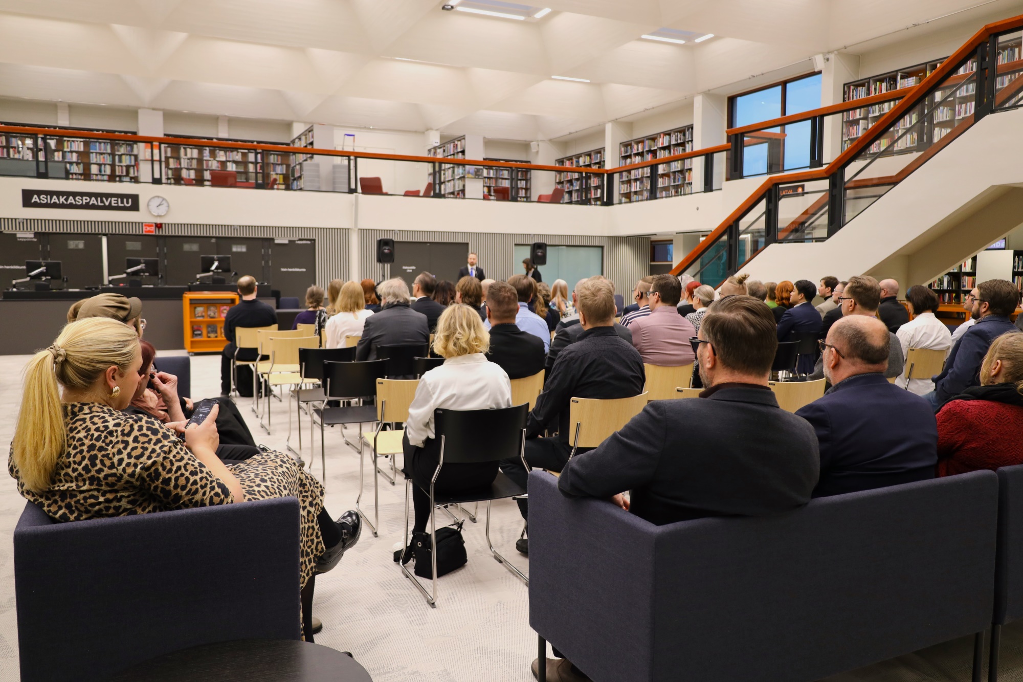 Ihmisiä kokoontuneena Lappeenrannan pääkirjastoon kuuntelemaan kaupunginjohtajan puheenvuoroa.